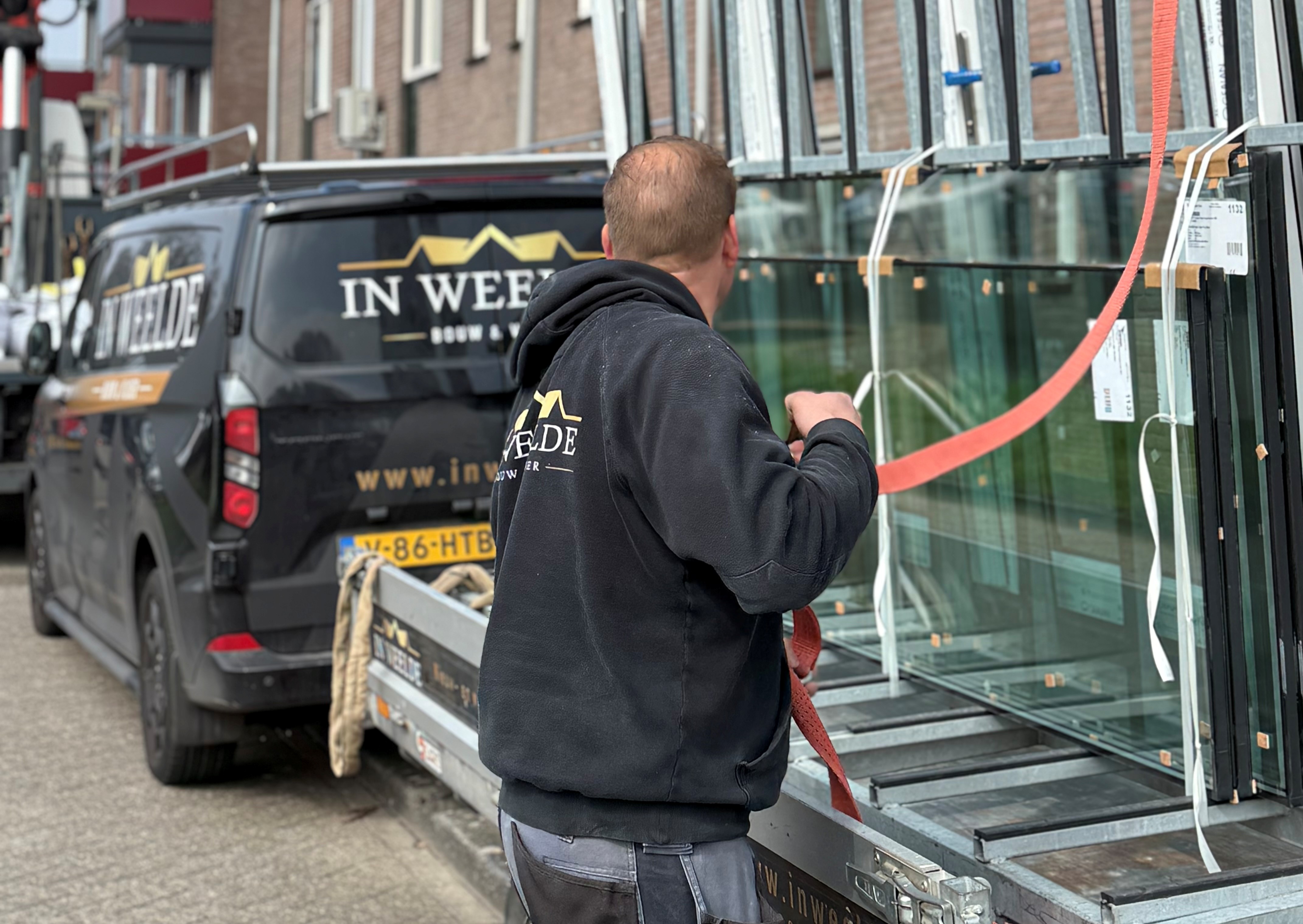 Medewerker van In Weelde plaatst een glaspaneel bij een woning in Purmerend